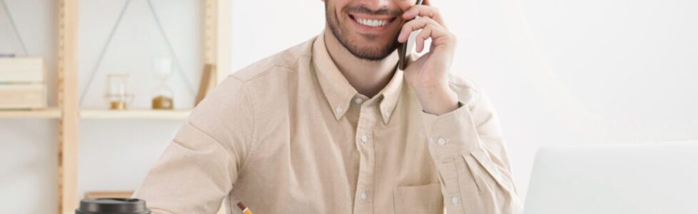 Young business man working in office, wearing blue shirt and eyeglasses, answering phone call